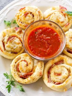 several small pastries with sauce in a glass dish on a white plate next to some parsley