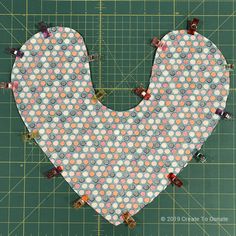 a heart shaped piece of fabric sitting on top of a cutting board