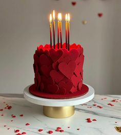 a red cake with hearts and candles on it