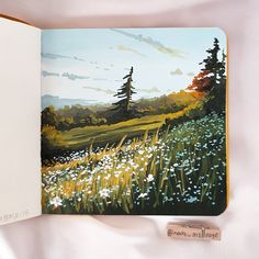 an open book with a painting of flowers and trees in the background on a white surface