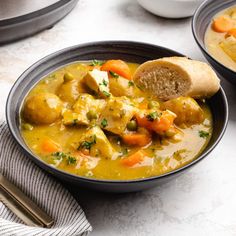 two bowls of soup with bread on the side