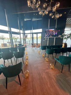 a room filled with lots of green chairs and lights hanging from the ceiling above them