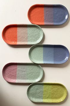 four oval trays with different colors on them