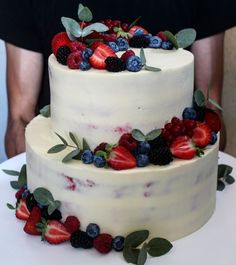 a triple layer cake with berries and leaves on top