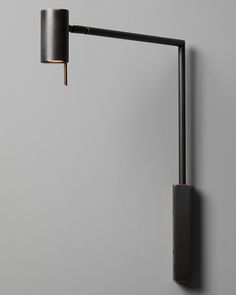 a black lamp on a gray wall next to a white wall with a grey background