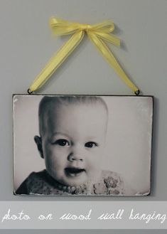 a baby's photo hanging on the wall with a yellow bow around its neck