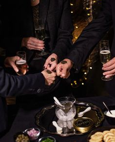 several people holding hands over a tray with food and drinks