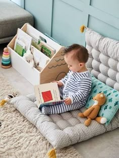 a baby is sitting on the floor reading a book