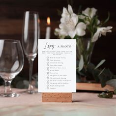 a table setting with place cards and wine glasses on it, along with white flowers