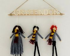 three dolls are hanging from a sign that says greyfindor