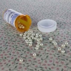 an open medicine bottle sitting on top of a table next to some white balls and a container