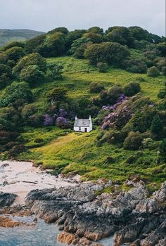 an aerial view of a house on the side of a hill with trees and bushes