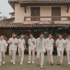 a group of men standing next to each other in front of a building with red flowers