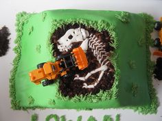 there is a cake that looks like a skeleton in the ground with construction vehicles on it