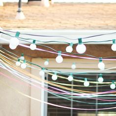 string lights hanging from the side of a building with green and white bulbs on them