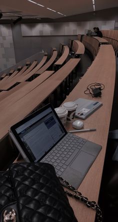 an open laptop computer sitting on top of a wooden table next to a black purse