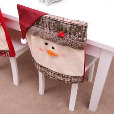 two snowmen sitting on top of white chairs at a table covered in christmas decorations