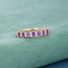 a pink sapphire and diamond ring sits on a green cloth