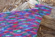 a multicolored knitted cloth hanging on a piece of wood