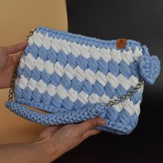 a hand holding a blue and white purse