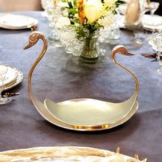 a table topped with plates and silverware next to a vase filled with yellow flowers