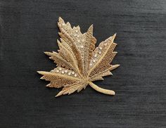 a gold leaf brooch sitting on top of a wooden table