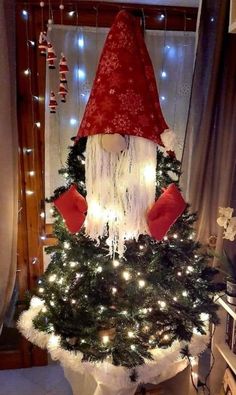 a christmas tree decorated with lights and a gnome's hat on top is shown