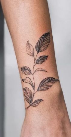 a woman's foot with a black and white leaf tattoo on the left ankle