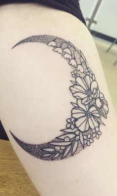 a black and white photo of a crescent tattoo on the right side of a woman's thigh