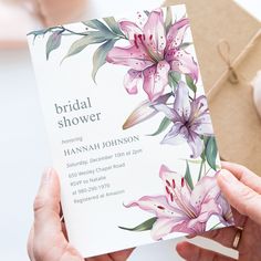 a woman holding up a wedding shower card with flowers on it and a gift bag in the background