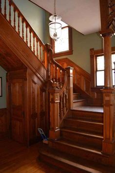 a wooden staircase leading to two windows and a light fixture hanging from the ceiling above it