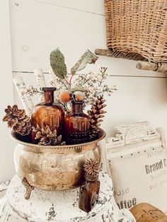 some bottles and pine cones are sitting in a basket on top of an old table