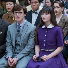 several people sitting next to each other in front of a crowd wearing suits and ties