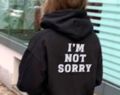 a woman wearing a black hoodie that says i'm not sorry