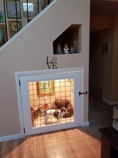 two dogs are sitting in their kennel under the stairs