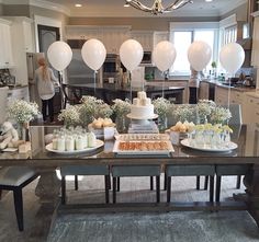 a table with cake, candles and balloons on it in the middle of a kitchen