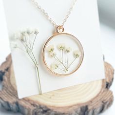 a necklace with flowers in it sitting on top of a piece of wood