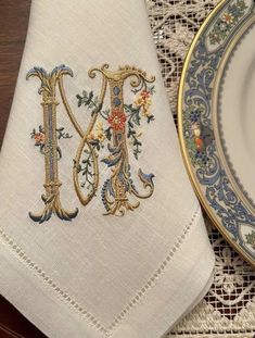 an embroidered monogrammed napkin sits next to a plate