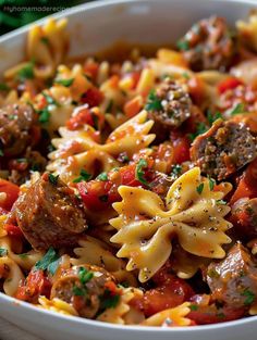 a white bowl filled with pasta and meatballs covered in tomato sauce, parsley