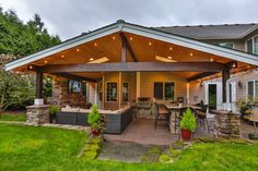 an outdoor covered patio with seating and lights on the roof, surrounded by green grass