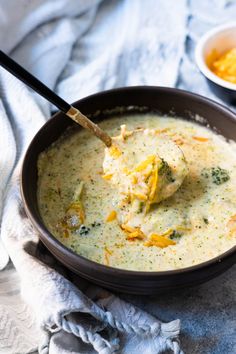 a bowl of broccoli cheese soup with a spoon in it