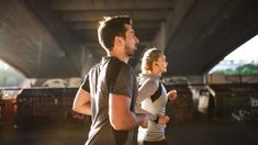 a man and woman jogging under an overpass