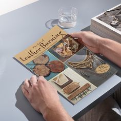 a person sitting at a table with a book and some jewelry on top of it