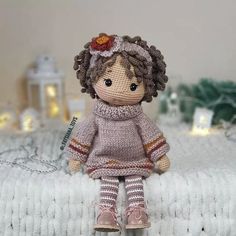 a knitted doll sitting on top of a bed