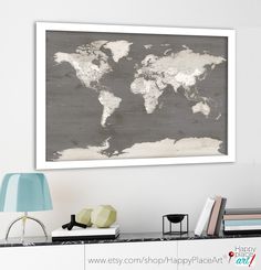 a white and gray world map hanging on the wall above a desk with a lamp