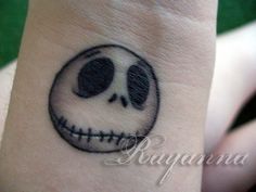 a small wrist tattoo with a skull on it