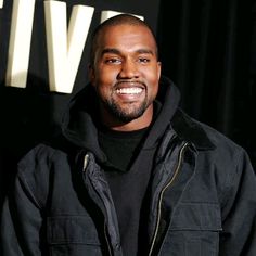 a man in a black jacket smiling at the camera