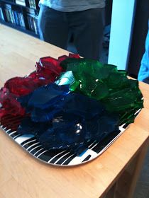 a plate with many different colored pieces of glass on it sitting on top of a wooden table