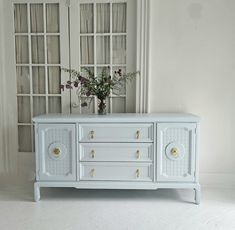 a vase with flowers sitting on top of a white dresser