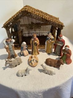 a nativity scene with figurines on a white table cloth covered tablecloth